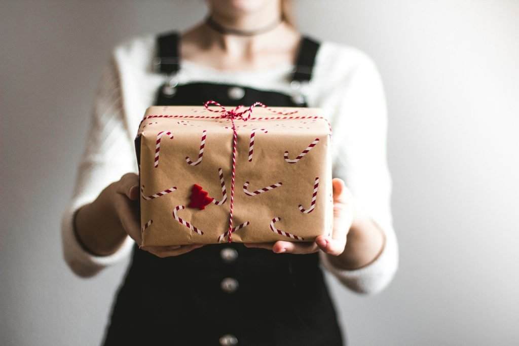 A woman holding a wrapped present for Christmas. Christmas affirmations gift